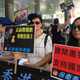 Protestors hold cartoons of Lam Wing-kee running away with a bag of money, and Albert Ho behind bars, “where he should belong.”